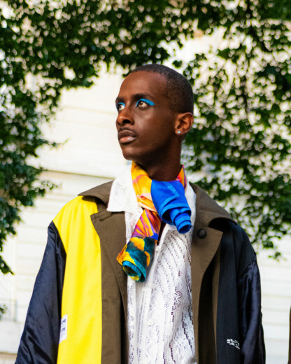 Foulard en soie jaune et bleu noué autour du cou d'un homme noir avec une veste jaune