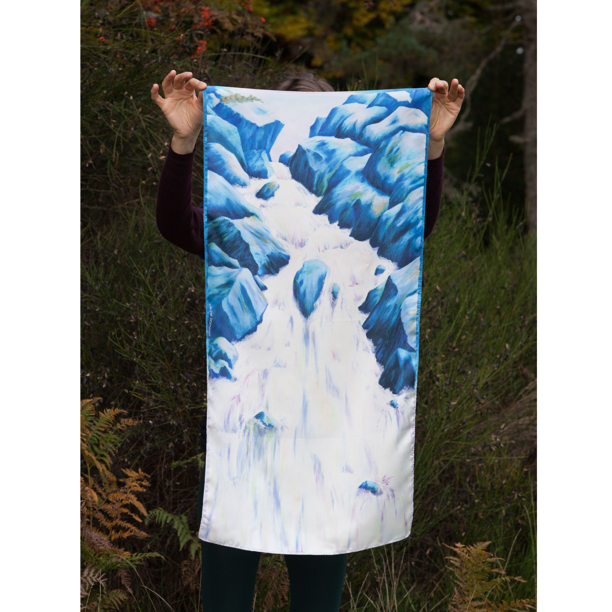 Foulard en soie motif Cascade coloris bleu tenu devant paysage automne