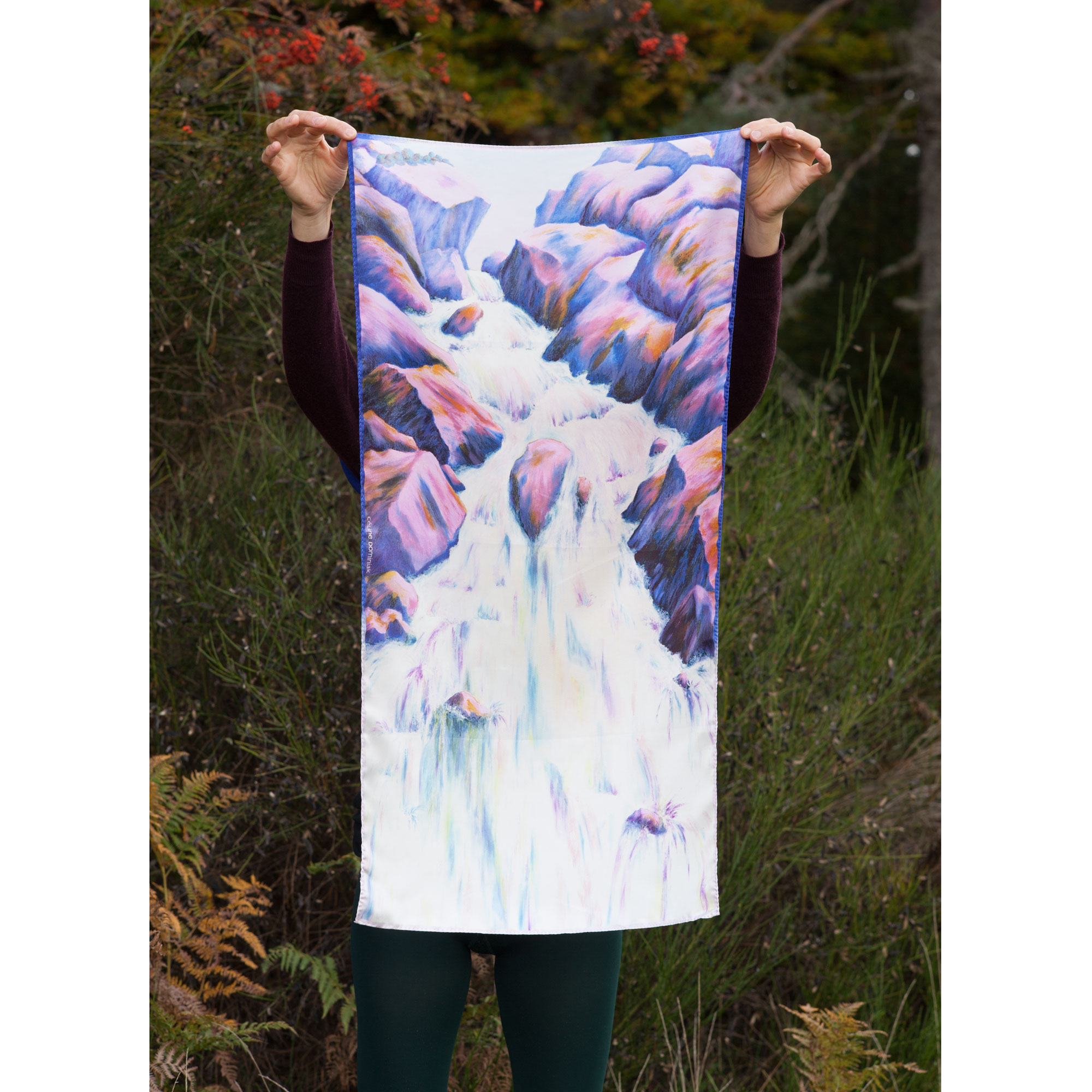 Foulard en soie motif Cascade coloris magenta tenu devant paysage automne